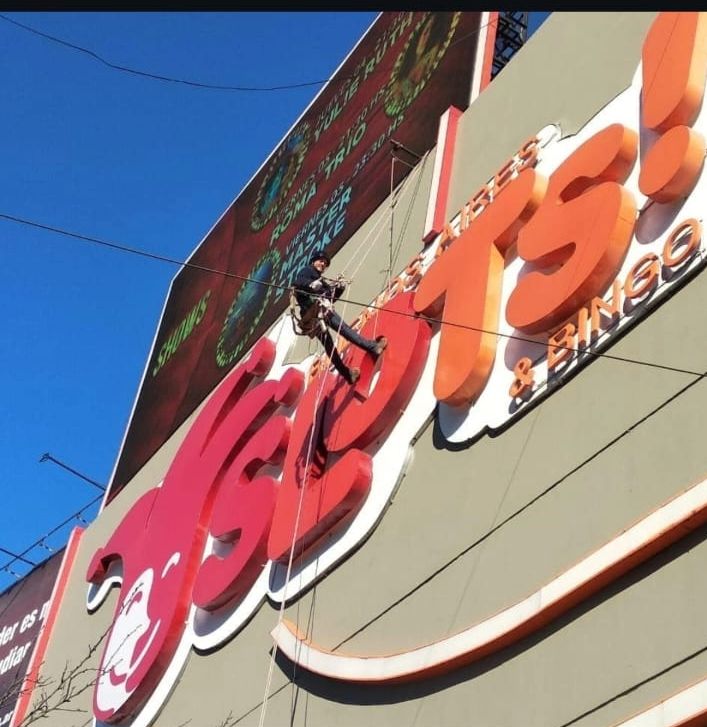 Técnico en cuerdas realizando el cambio de una lona publicitaria de gran formato en Avellaneda
