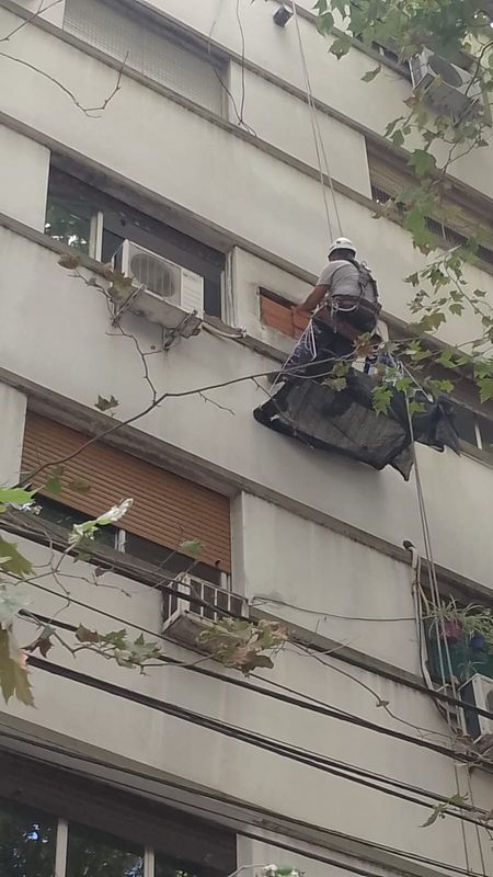Técnico en acceso por cuerdas bajando un equipo de climatización por la fachada