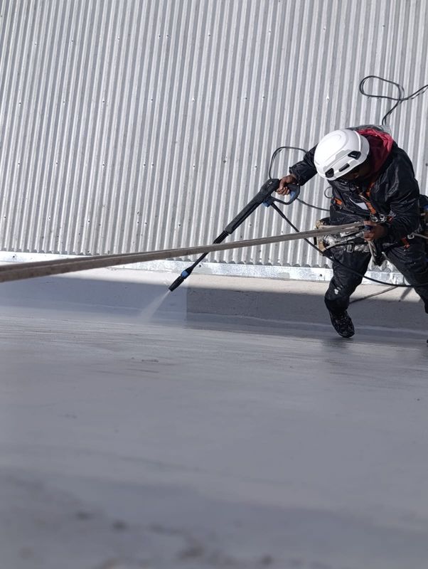 Técnico en cuerdas realizando hidrolavado de medianera en Villa Urquiza