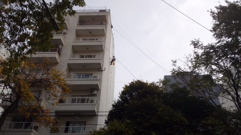Vista general de medianera en impermeabilización con técnicos en cuerdas, Monte Castro