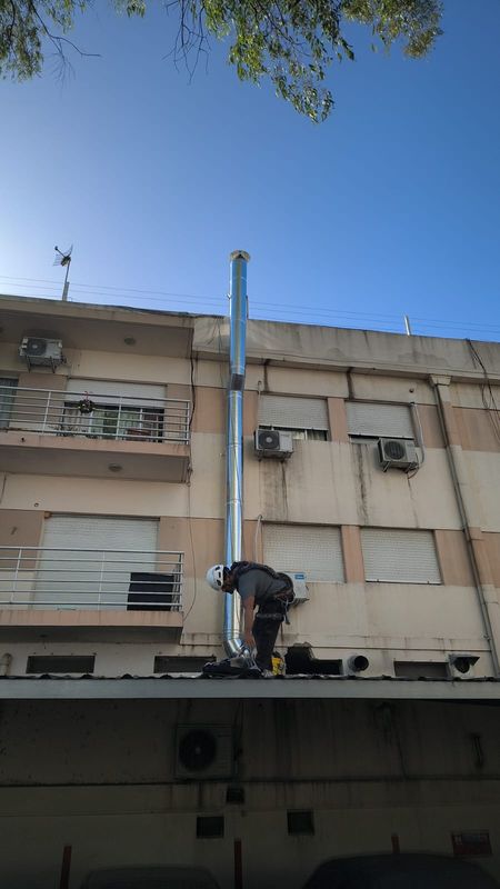 Técnico en altura fijando un ducto de extracción vertical sobre fachada de edificio