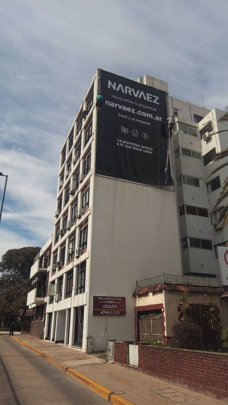 Técnicos en cuerdas tensando una gigantografía sobre medianera en San Isidro