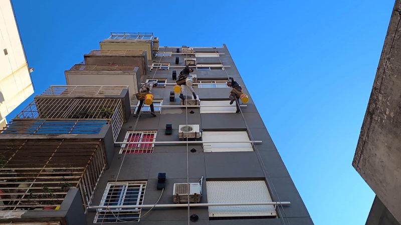 Técnicos en acceso por cuerdas pintando el contrafrente de un edificio