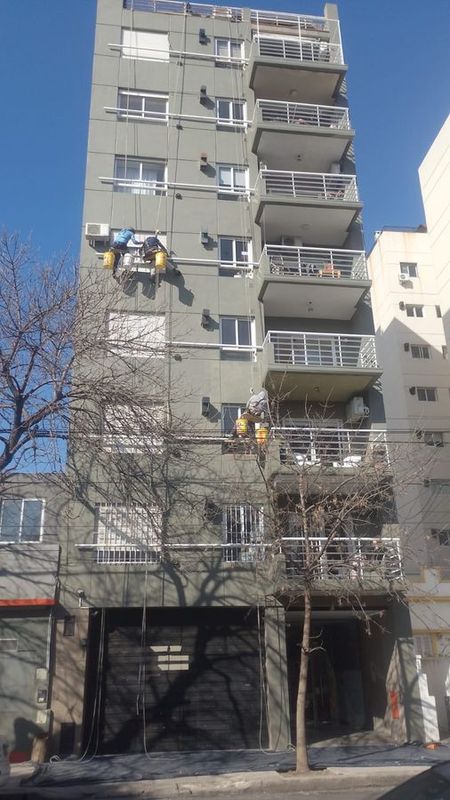 Técnicos en acceso por cuerdas pintando la fachada de un edificio residencial en CABA