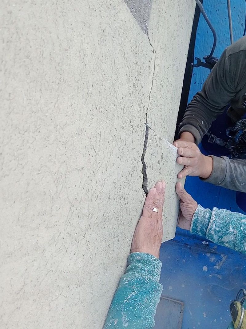 Técnico en acceso por cuerdas retirando a mano el revoque flojo del frente de un balcón
